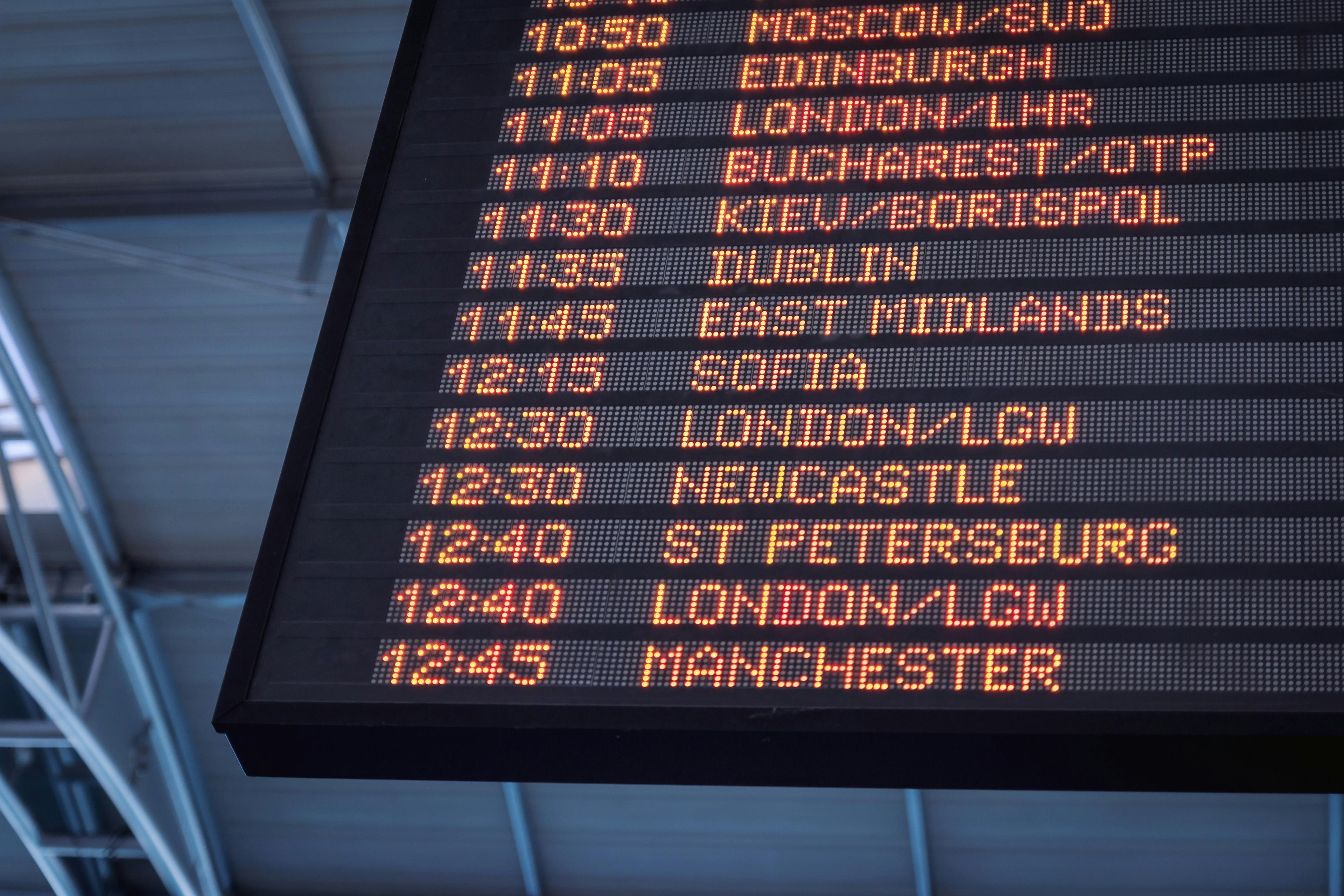 A close-up view of an illuminated airport departures board listing destinations and times.